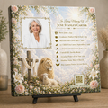 Memorial plaque with a portrait of a woman, cross, lion, and lamb design on a wooden surface.